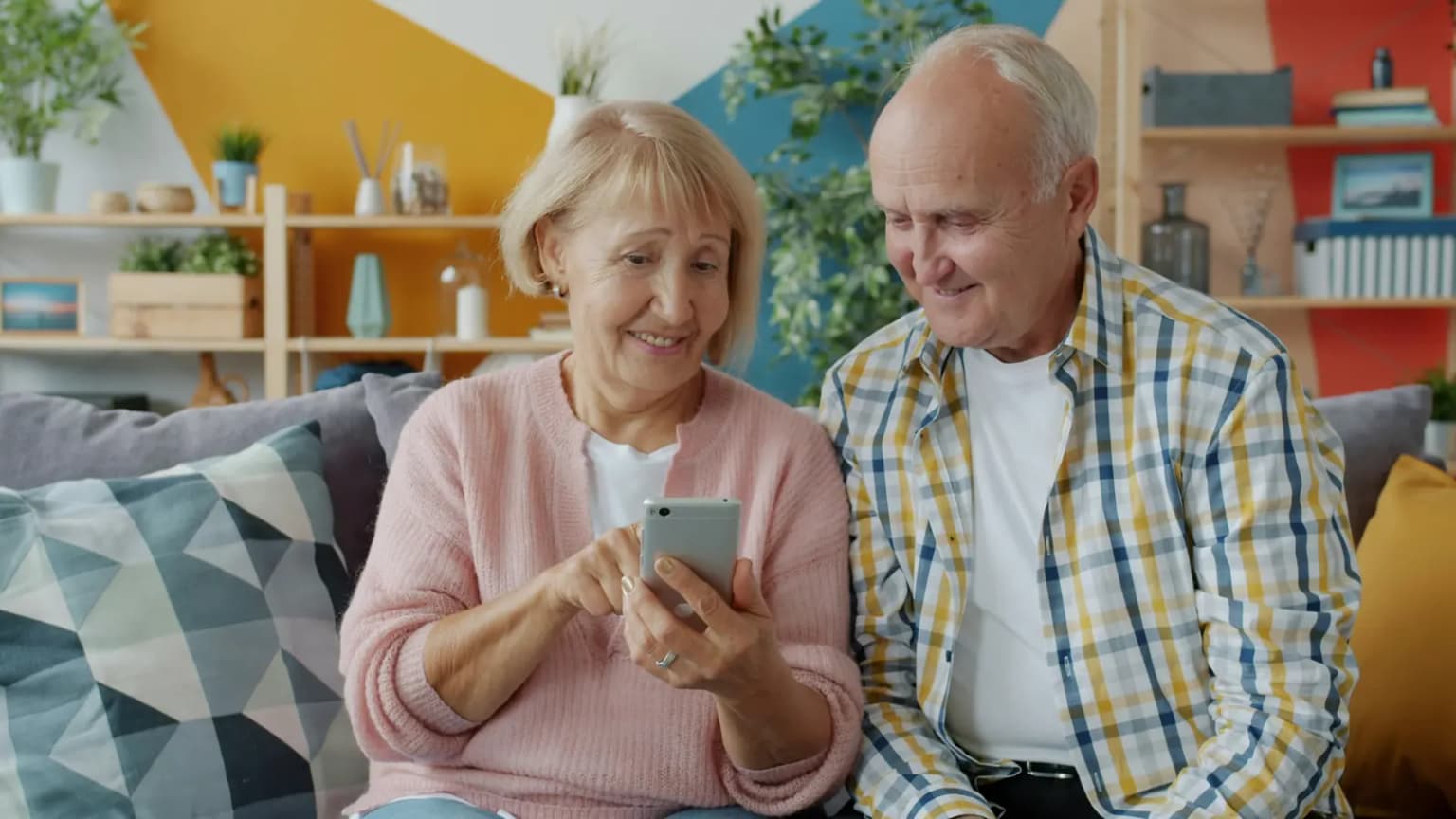 Una pareja mayor en un sofá mirando juntos un teléfono