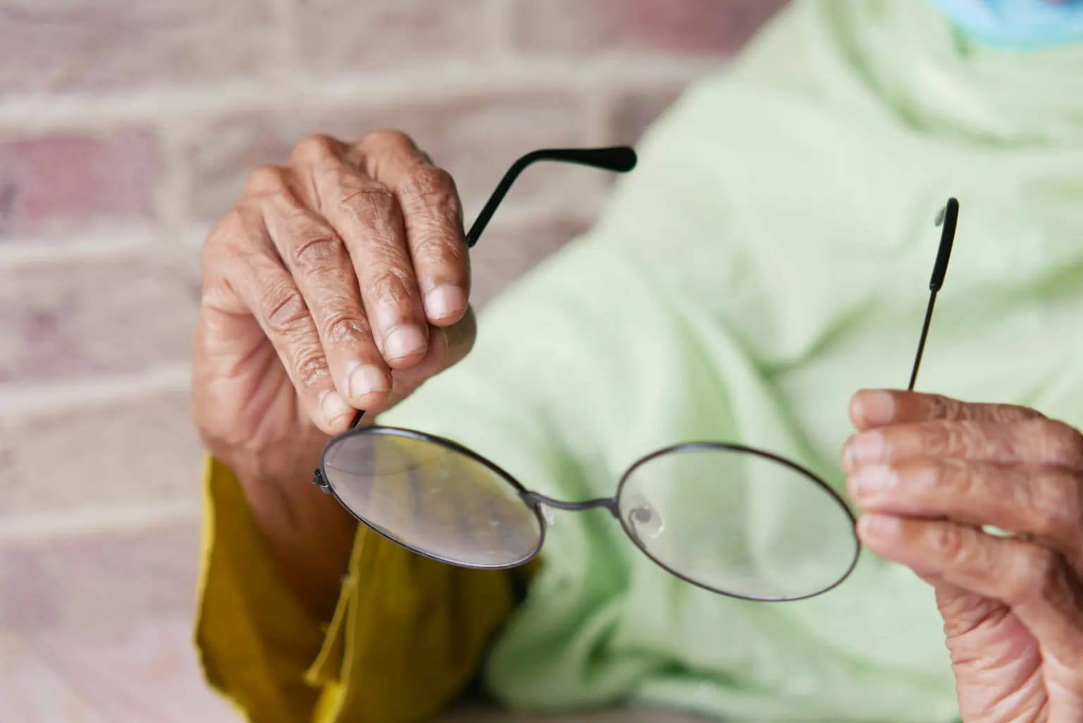 Una persona mayor sosteniendo sus anteojos mientras lee